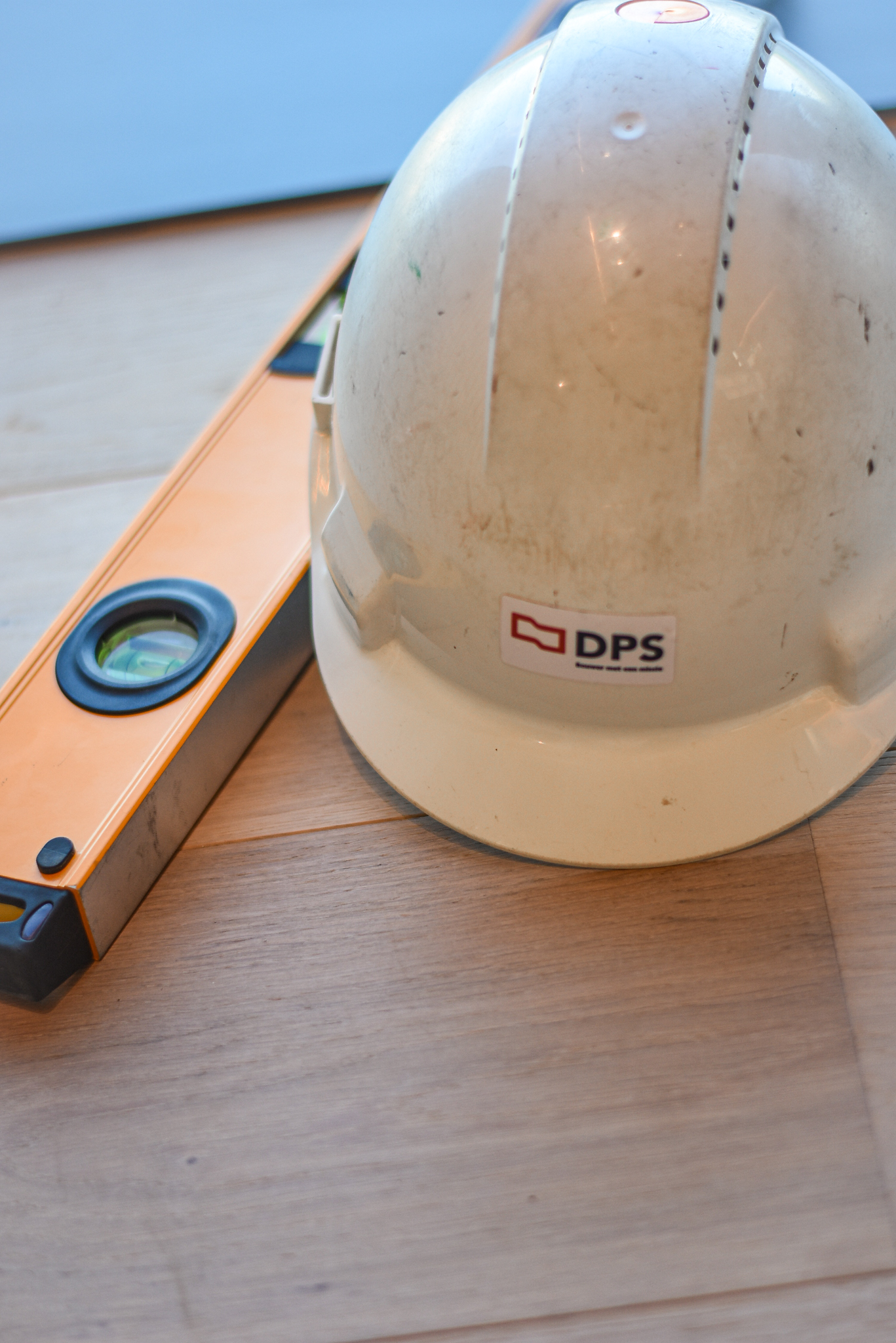 Veiligheidshelm met DPS-logo en waterpas op de werf